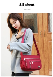Detail of burgundy nylon crossbody bag featuring multi-zipper pockets and wide strap