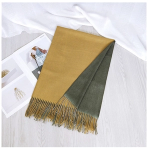 Close-up of double-sided two-tone scarf in ginger and dark green with fringe detail