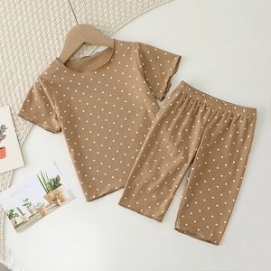 Close-up of baby pajamas set featuring caramel polka dots and textured ribbed knit fabric