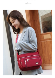 Detail of red nylon crossbody bag featuring multiple zipper compartments and adjustable strap