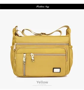 Detail view of yellow oxford cloth shoulder bag featuring multi-zipper pockets and hardware