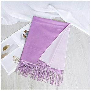 Detail of two-tone purple scarf with fine tassels on a rustic grey wood surface