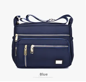Close-up of blue Oxford fabric shoulder bag featuring durable zippers and gold hardware