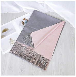 Close-up of pink and grey double-sided scarf with elegant tassels on soft wood floor