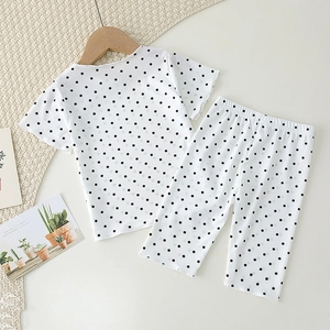 Detail of baby summer pajama set with black polka dots on white ribbed knit fabric