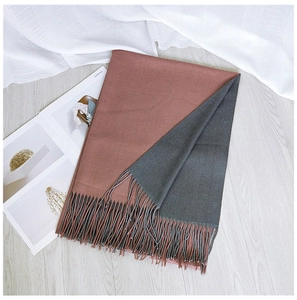 Close-up of two-tone pink and grey scarf with fringe tassels on light wood background