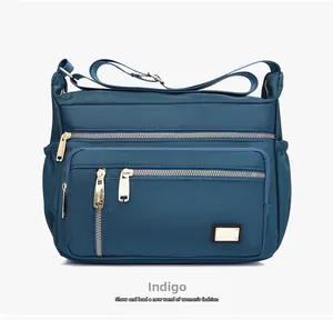 Detail of teal oxford fabric bag showing multi-layer zipper pockets and adjustable strap