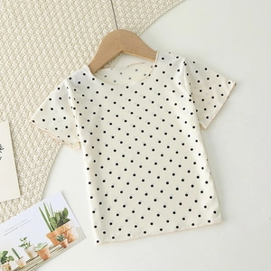 Detail of baby girl summer t-shirt with black polka dots and ruffled edges in ribbed fabric