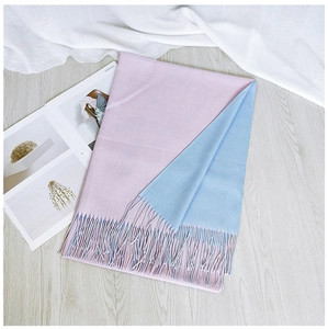 Detailed macro view showing the soft texture and tassel fringe of the pink and blue scarf