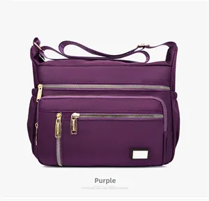 Detail view of purple nylon crossbody bag with multiple gold zippers and compartments