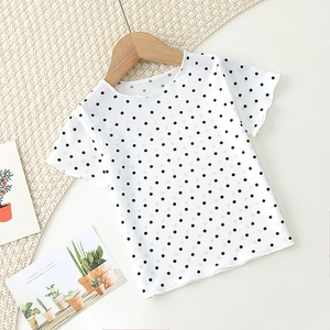 Detail of baby summer pajama top with black polka dots and wave ruffled edges