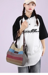 Détail du sac cabas en toile rayée multicolore avec lanières en cuir porté par un modèle