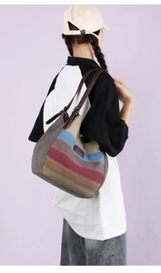Détail d'un grand sac bandoulière en toile rayée avec lanières en cuir porté par un mannequin