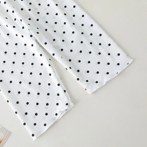 Close-up of baby pajama wide-leg pants with black polka dots and ribbed knit texture