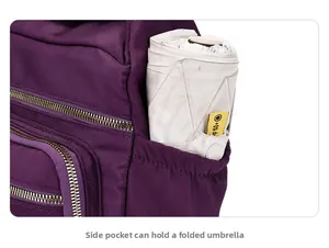 Detail view of the side elastic pocket on the purple oxford bag holding a folded umbrella
