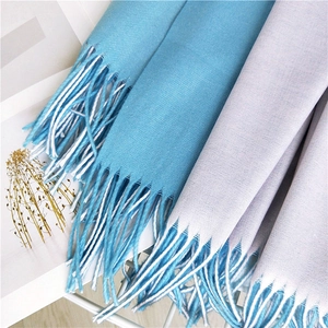 Detail of soft twill weave texture and long tassels on light blue and gray winter scarves