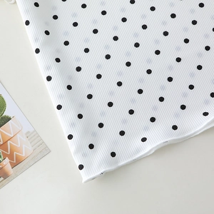 Detail of white ribbed cotton fabric with black polka dots and lettuce edge hem