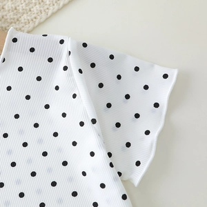 Close-up of girls' summer ribbed pajamas featuring black polka dots and wavy ruffle cuffs