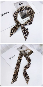 Détail d'un foulard twilly léopard avec pointes biseautées sur fond de magazine de mode
