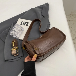 Chic dark brown faux leather saddle bag with vintage patterned strap on grey blazer
