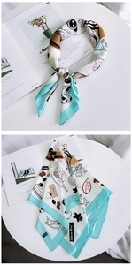 Detail of silk scarf with cartoon cat and milk orange print on white and green background