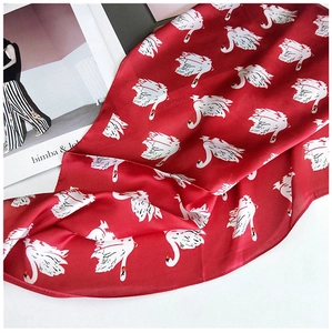 Gros plan d'un foulard en soie rouge avec imprimés cygnes et texture soyeuse