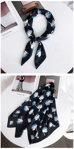 Détail d'un foulard en soie noir avec motif de cygnes blancs et vagues bleues