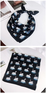 Détail d'un foulard en soie noire avec motif cygne blanc et vagues bleues élégantes