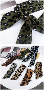 Détail de foulards en polyester à imprimé léopard multicolore sur une table blanche