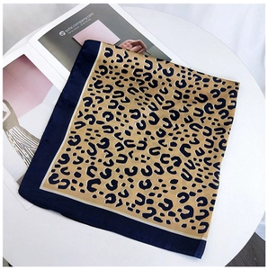Detail view of square leopard print silk scarf on a magazine over a white table