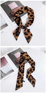 Détail d'un foulard étroit à motif léopard noué sur un magazine dans un décor élégant