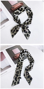 Détail du petit foulard en soie 100% avec motif léopard noué sur un magazine