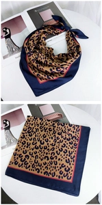 Detail of leopard print silk scarf with deep blue border and red accent stripes