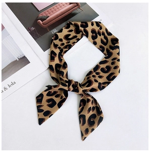 Détail d'un foulard en soie léopard noué en boucle à côté d'un magazine de mode