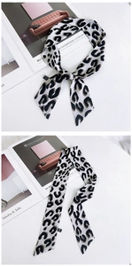 Détail d'un foulard étroit imprimé léopard noué en boucle montrant la texture soyeuse
