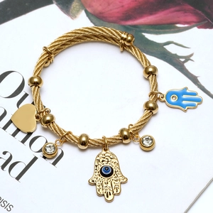 Detail of 18K gold-plated steel wire bracelet with Hamsa Hand and Evil Eye charms