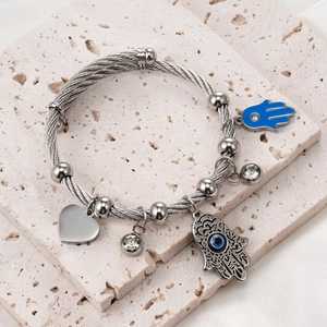 Detail of silver wire bracelet with Hamsa charms and blue enamel eye on stone