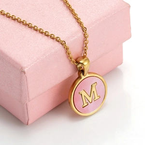 Close-up of 18K gold stainless steel necklace with pink shell pendant and letter M