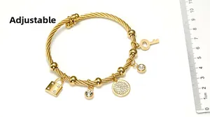 Close-up of adjustable gold steel bracelet with charms and ruler for size scale