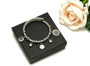 Close-up of silver steel cable bracelet with Tree of Life charm and crystal pendant