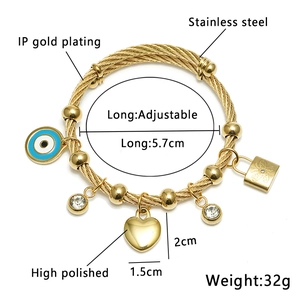 Detailansicht eines goldenen Stahldraht-Armbands mit Evil Eye und Herzanhänger
