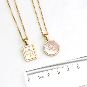 Dettaglio di ciondoli zodiacali in oro 18 carats con conchiglia rosa e righello