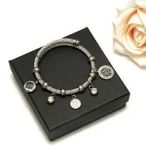 Silver twisted cable bracelet with Tree of Life and crystal charms on a gift box