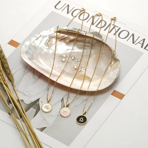 Dettaglio macro di ciondoli zodiacali placcati oro 18K su conchiglia iridescente