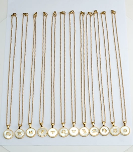 Dettaglio di dodici collane zodiacali in oro 18K con inserto in madreperla su sfondo bianco
