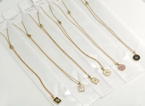 Dettaglio di collane zodiaco placcate oro 18 carati con inserti in conchiglia su bianco