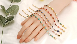 Makroaufnahme bunter Evil-Eye-Armbänder mit verstellbaren Goldketten am Handgelenk