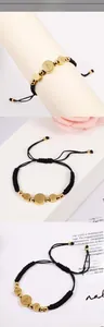 Macro detail of Saint Benedict religious charms on black braided rope bracelet with gold beads