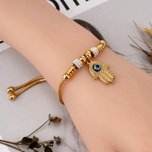 Gold snake chain bracelet with Hamsa Hand and Evil Eye charms on a female wrist