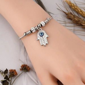 Polished silver Hamsa hand bracelet with blue evil eye charm and crystal beads on wrist